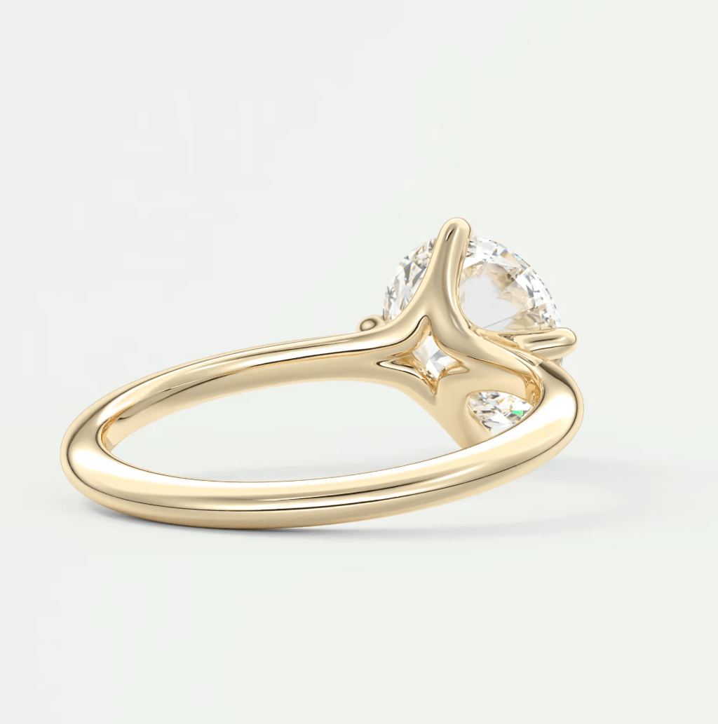 18-karat gold engagement ring with a pear-shaped diamond and two smaller round diamonds, featuring an elegant split shank design.