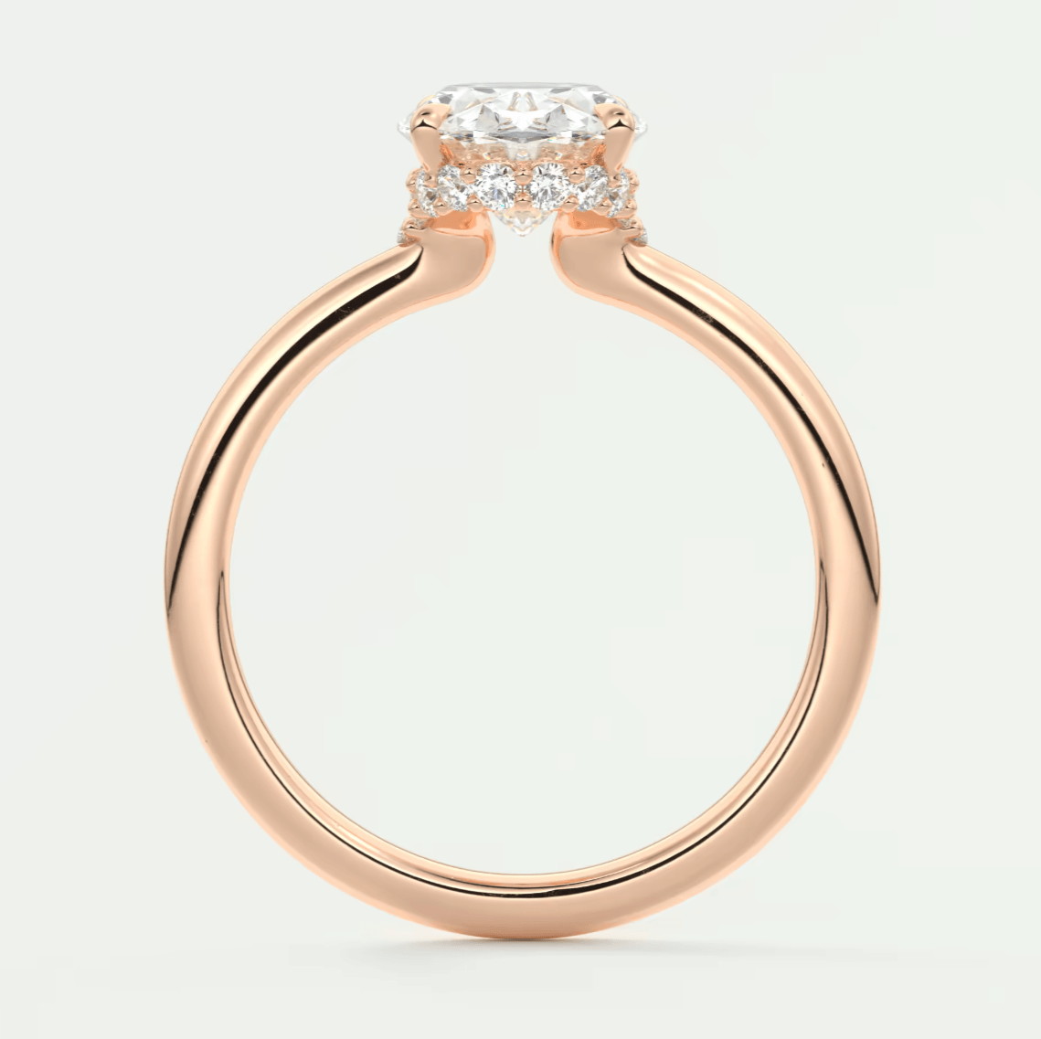 Rose gold engagement ring with a cushion-cut diamond and smaller diamonds set in the band, featuring an elegant halo design.
