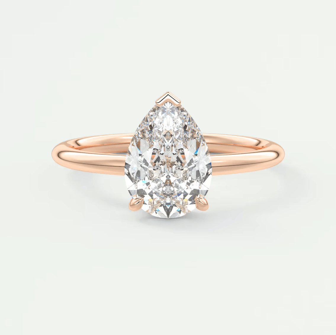 Rose gold pear-shaped diamond engagement ring with a solitaire design.