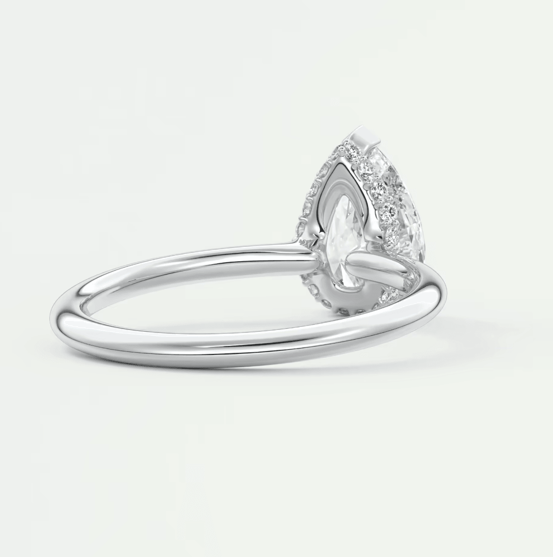Pear-shaped diamond engagement ring with halo of smaller diamonds, white gold or platinum.
