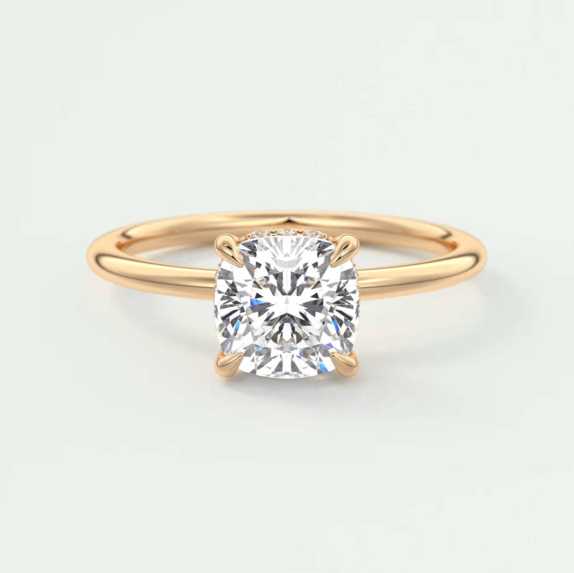 18-karat rose gold engagement ring with a cushion-cut diamond.