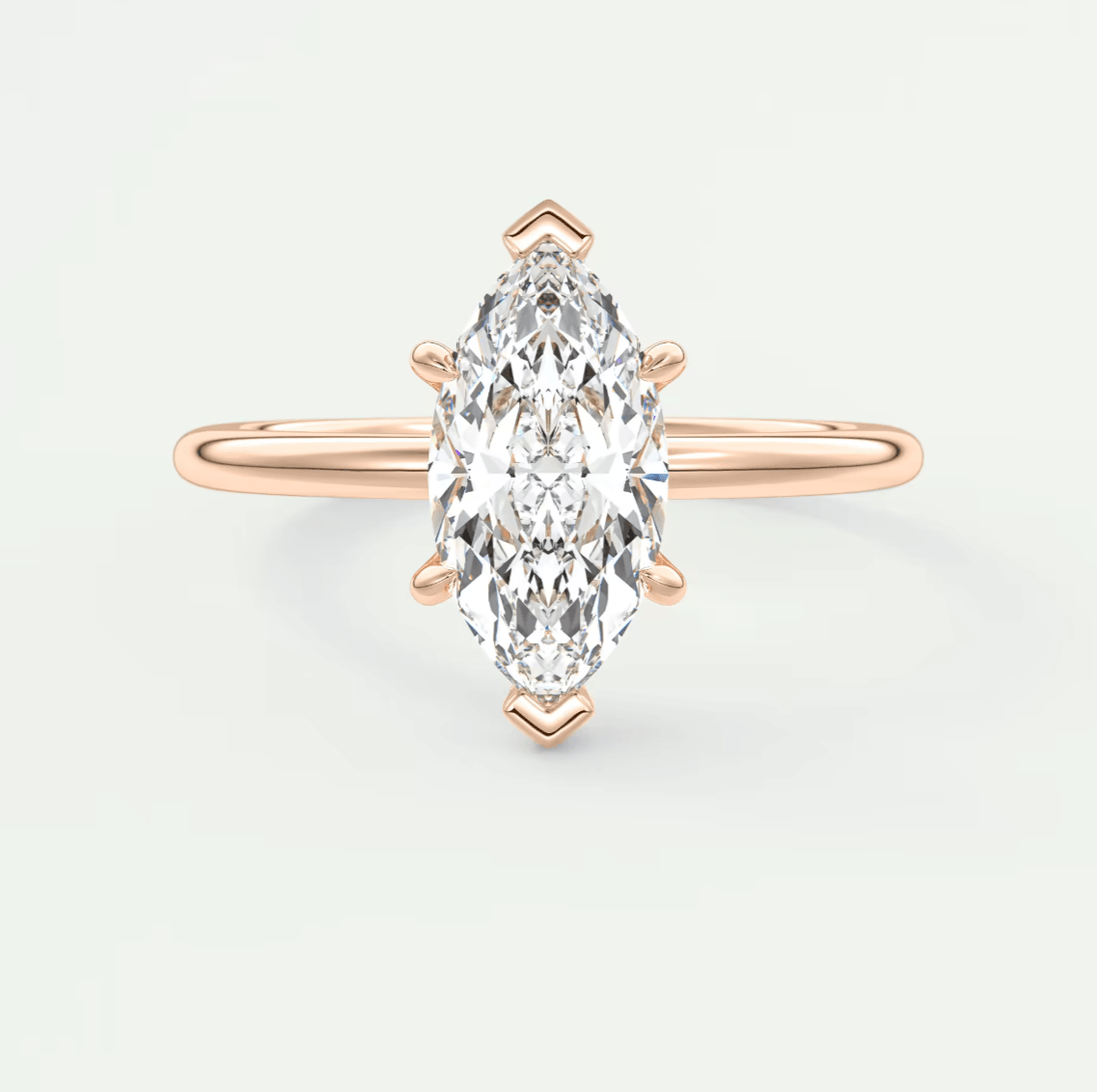 Rose gold marquise diamond engagement ring with a single stone setting and delicate band design.