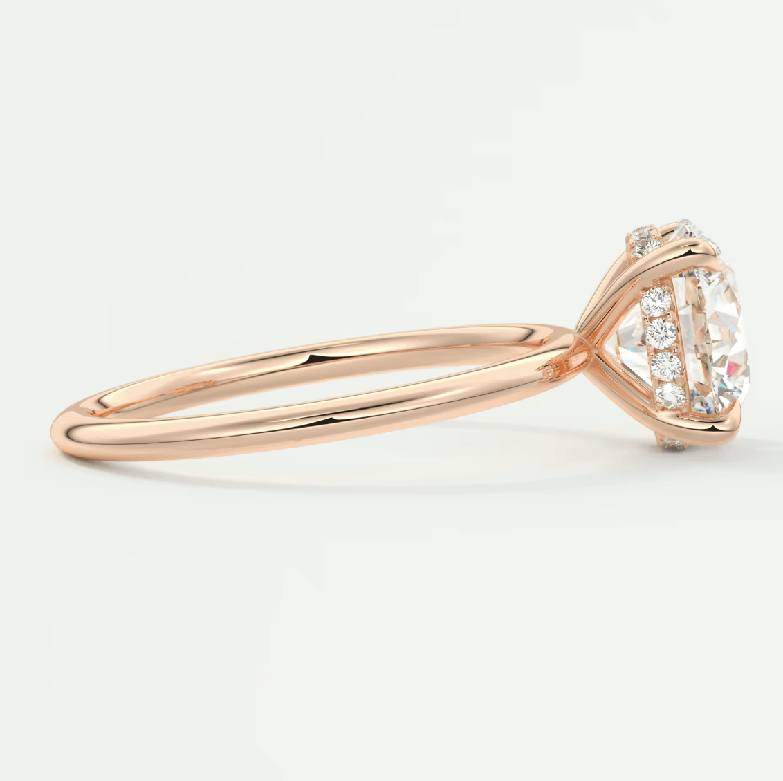 18-karat rose gold engagement ring with a round diamond center and halo of smaller diamonds.