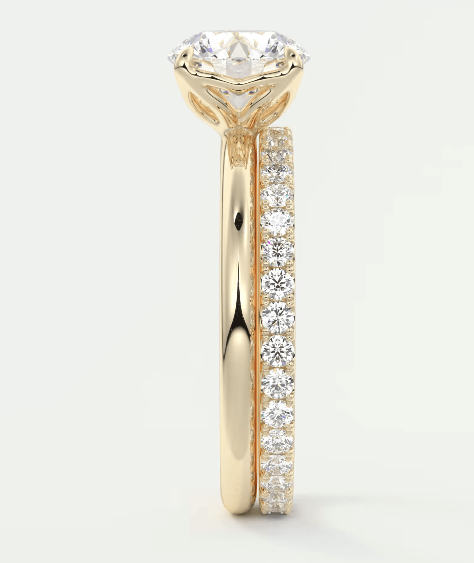 18k yellow gold engagement ring with a round diamond center and pavé side stones.