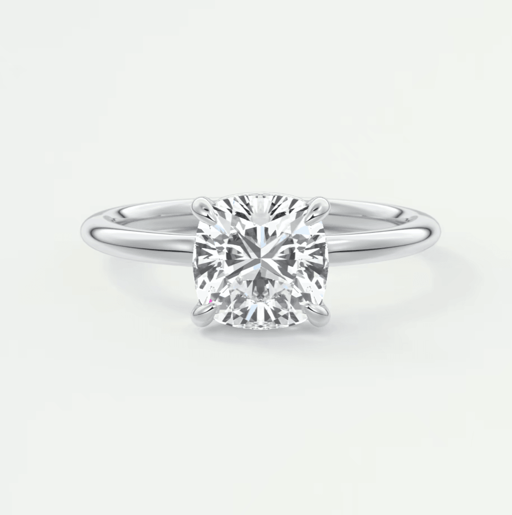 Cushion-cut diamond engagement ring with white gold band, featuring a central stone and four prongs.
