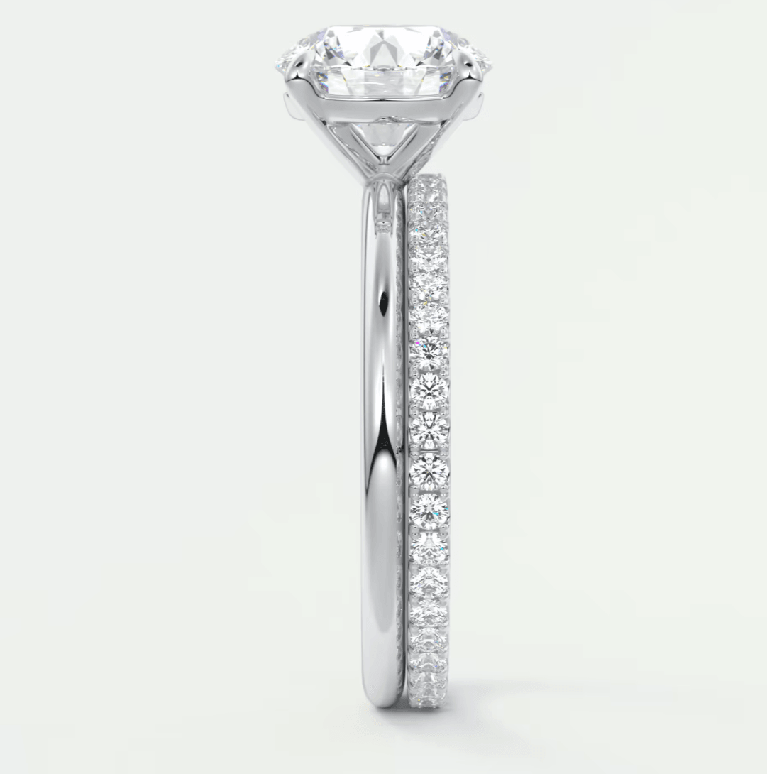 18k white gold engagement ring with a round diamond center stone and pave set diamonds on the band.