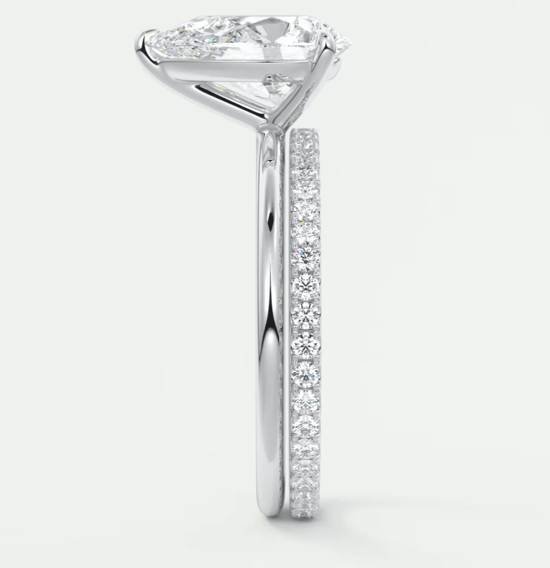 18-karat white gold engagement ring with a pear-shaped diamond and pave-set diamonds on the band.