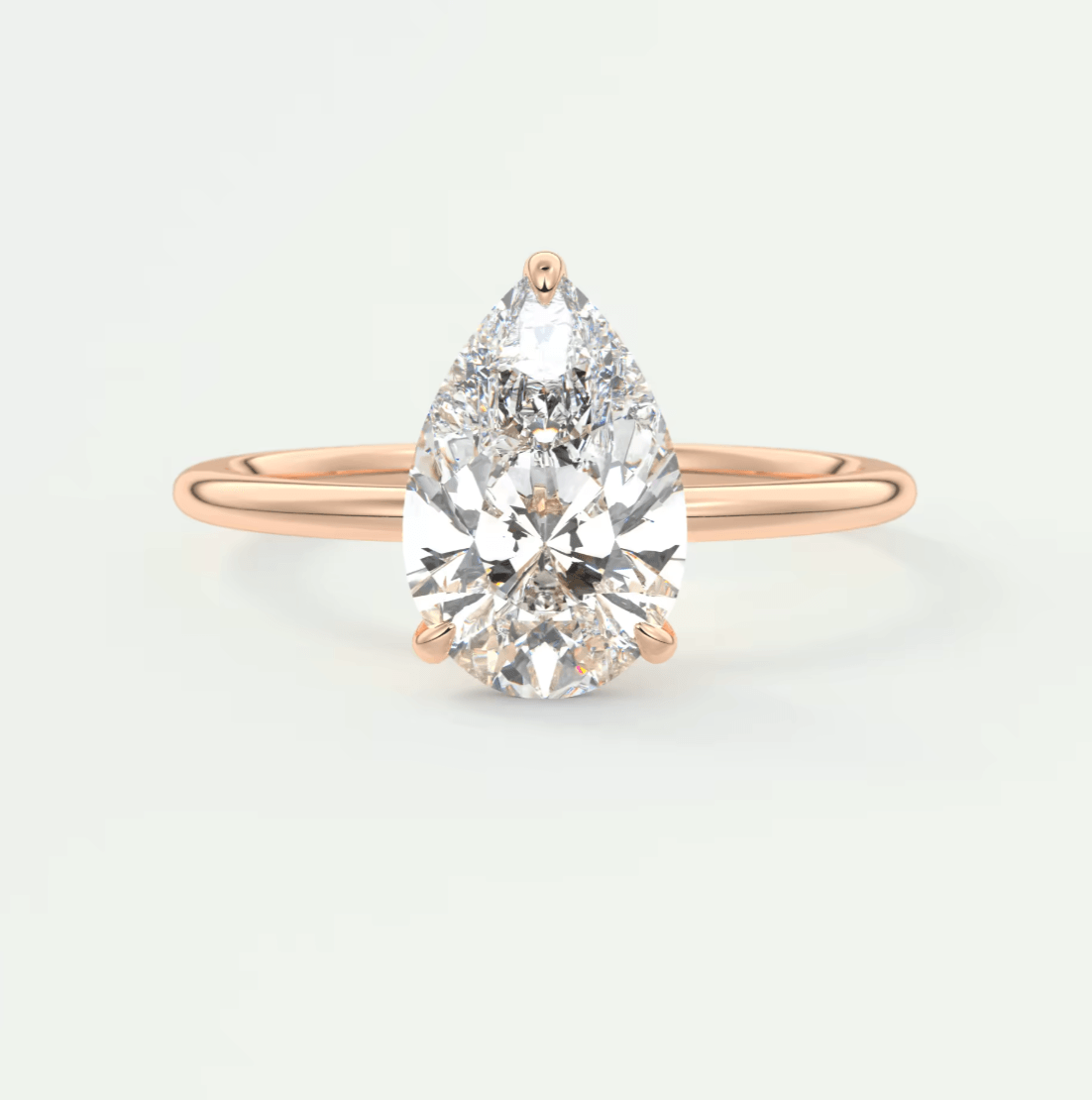 Rose gold pear-shaped diamond engagement ring with a solitaire design.