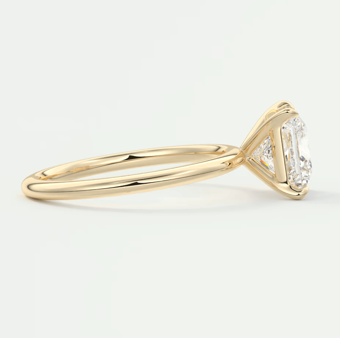 18k yellow gold engagement ring with emerald-cut diamond center stone and small round diamonds on the band.