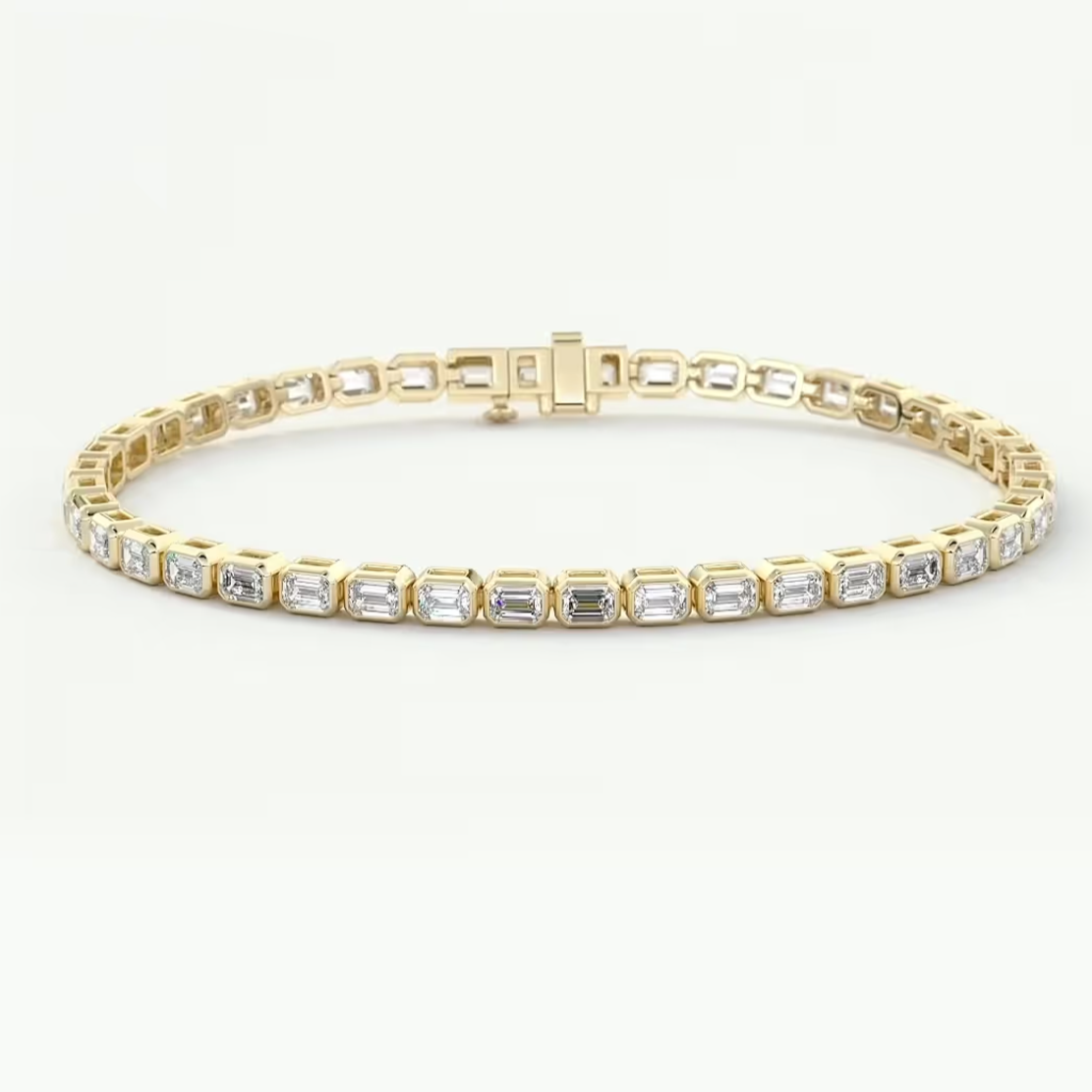 A yellow gold tennis bracelet featuring a row of baguette-cut clear gemstones, displayed on a clean white background.
