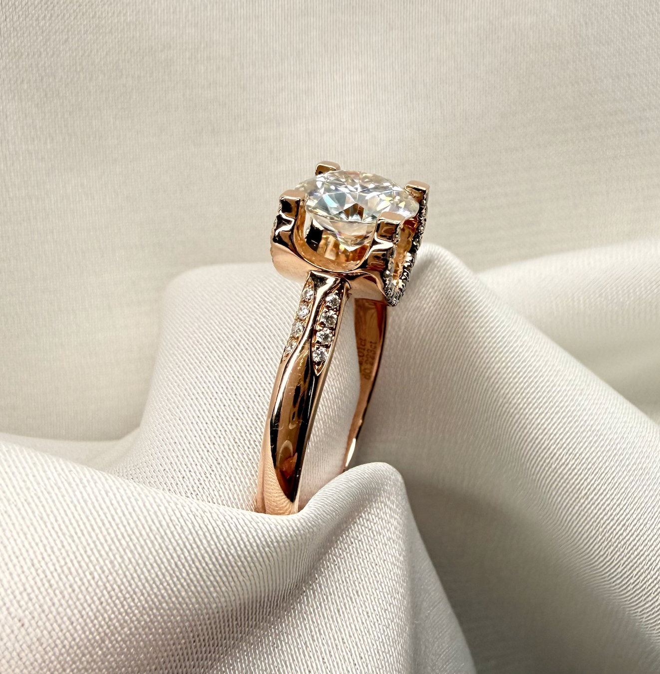 Rose gold ring with a large diamond on a white fabric background