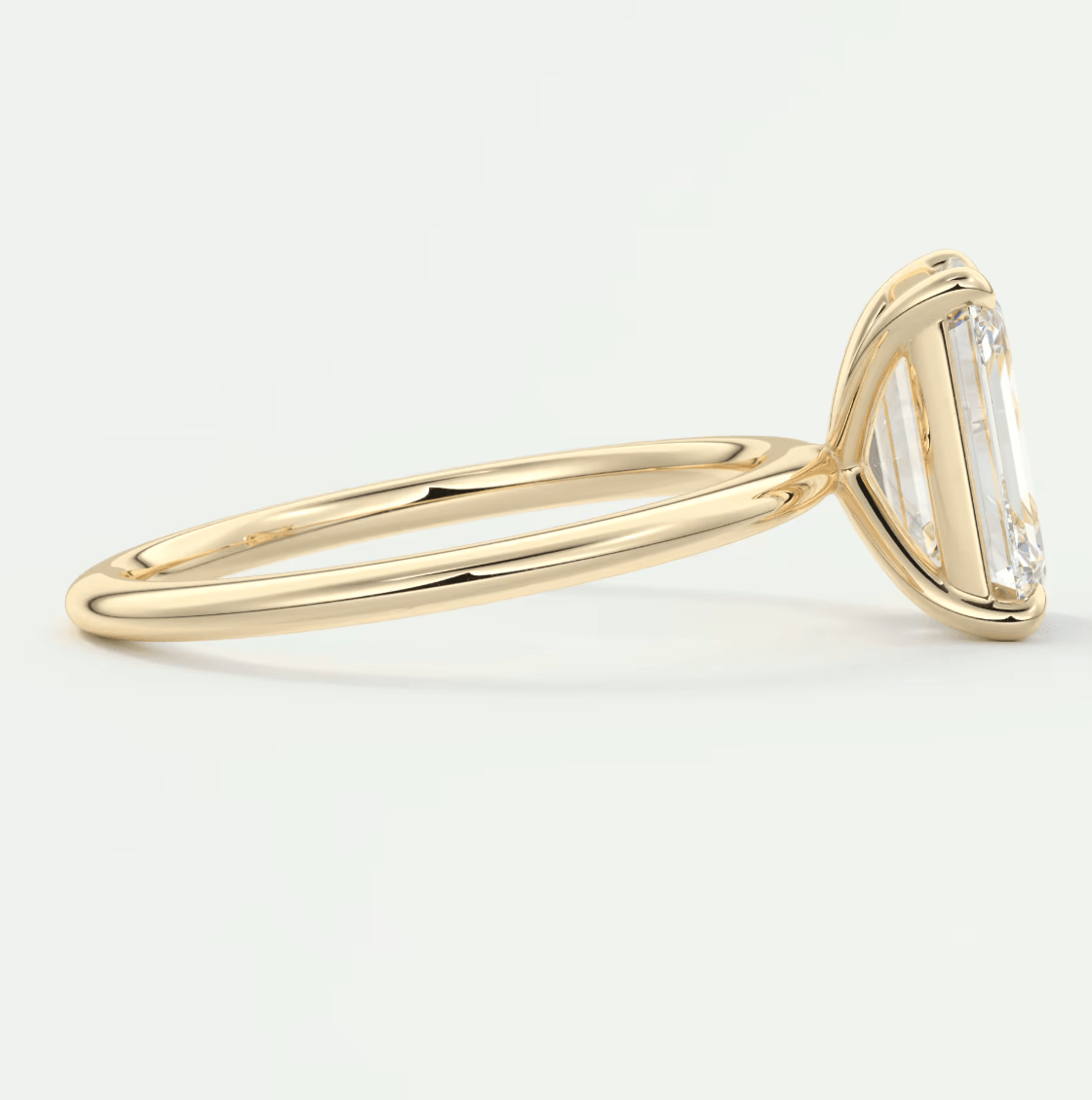18-karat yellow gold engagement ring with a baguette-cut diamond.
