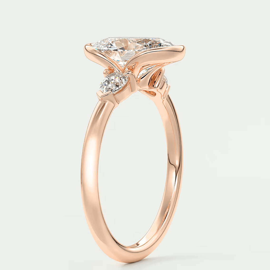 Rose gold diamond engagement ring with a marquise-cut center stone and two smaller diamonds on each side.