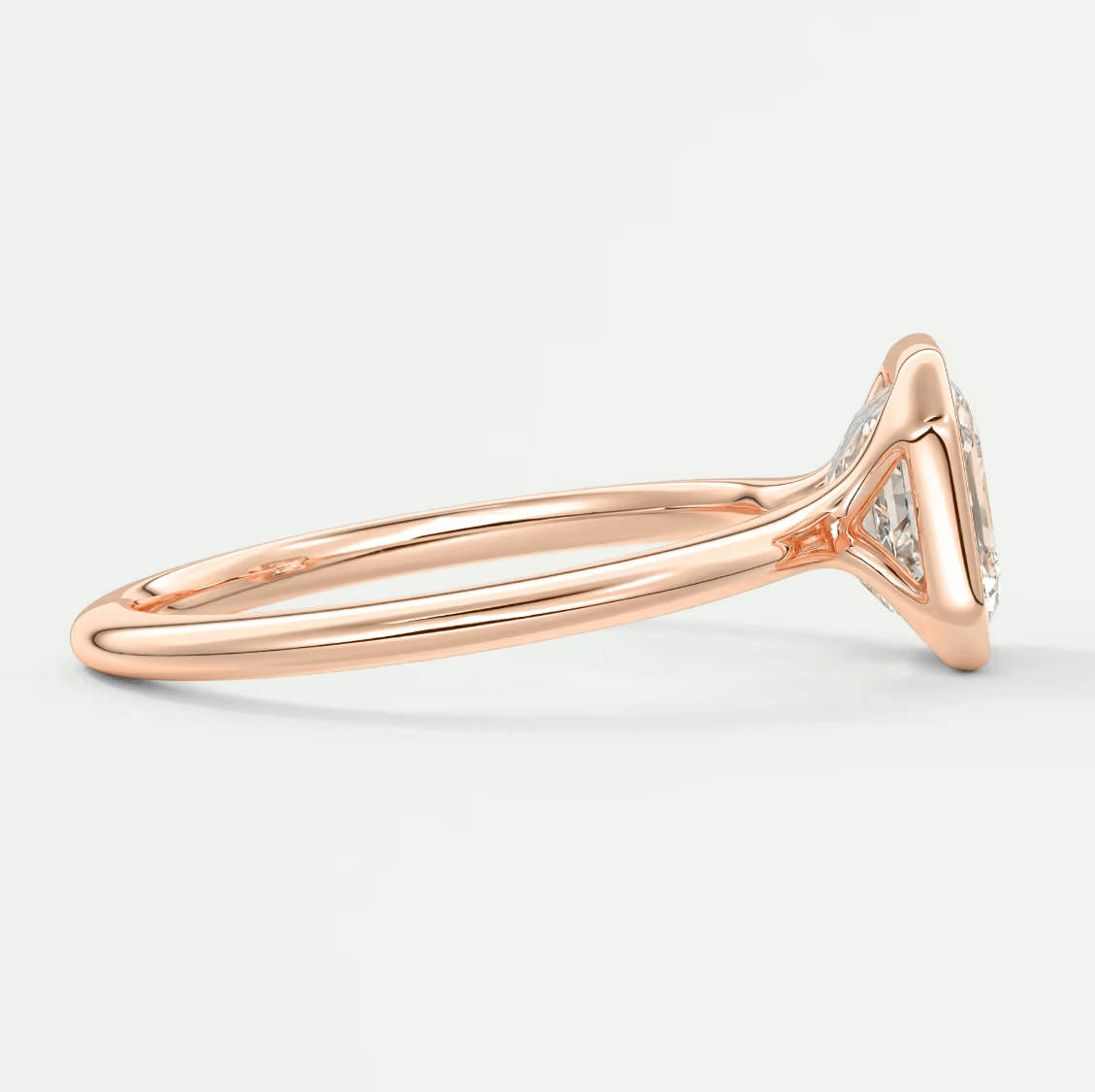 Rose gold diamond engagement ring with a cushion-cut center stone and small side diamonds set in an elegant bezel setting.