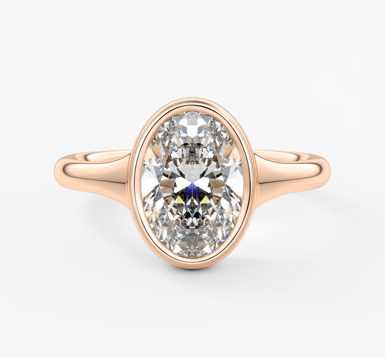 Rose gold oval diamond engagement ring with a bezel setting.