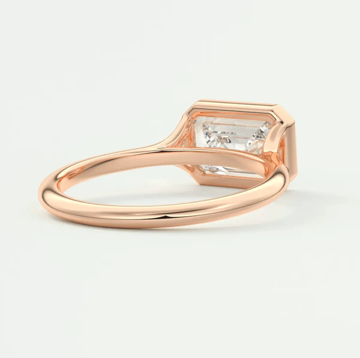 18-karat rose gold engagement ring with an emerald-cut diamond.
