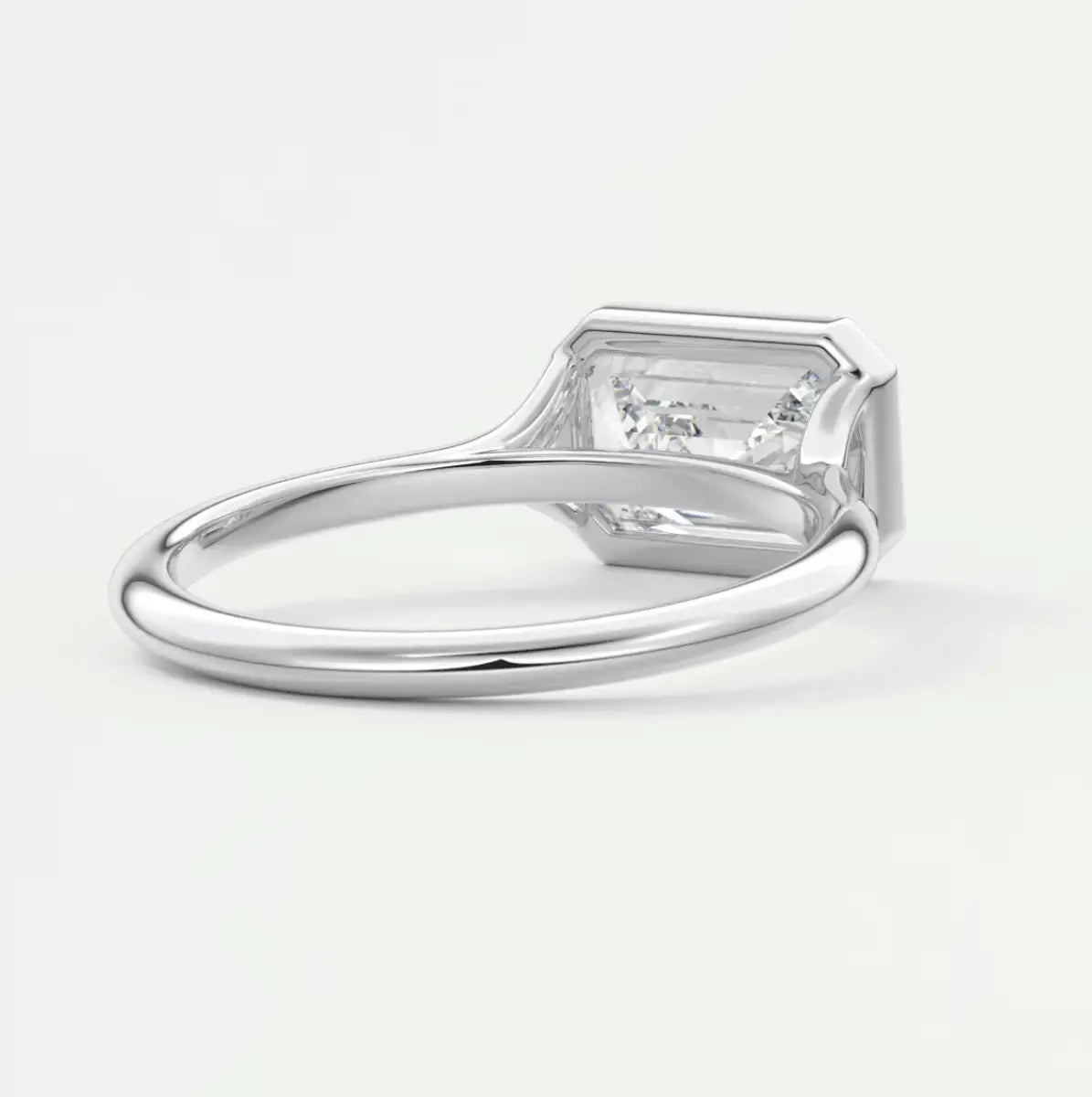Silver diamond engagement ring with a rectangular cut gemstone and small side stones.