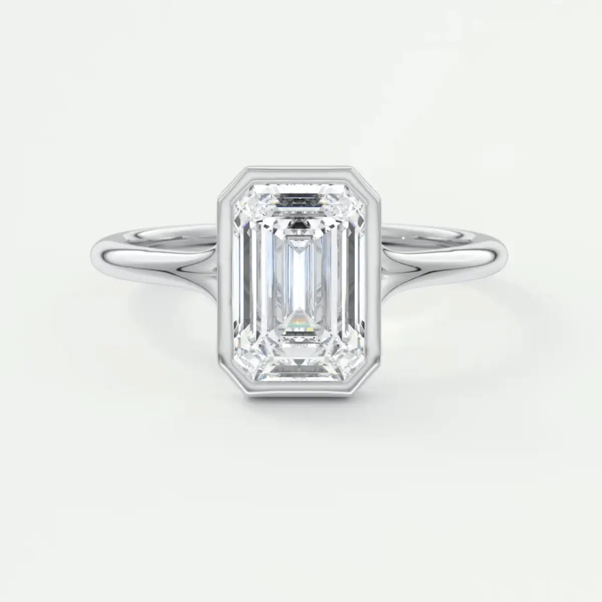 18k white gold emerald cut diamond engagement ring with a bezel setting and milgrain detailing.