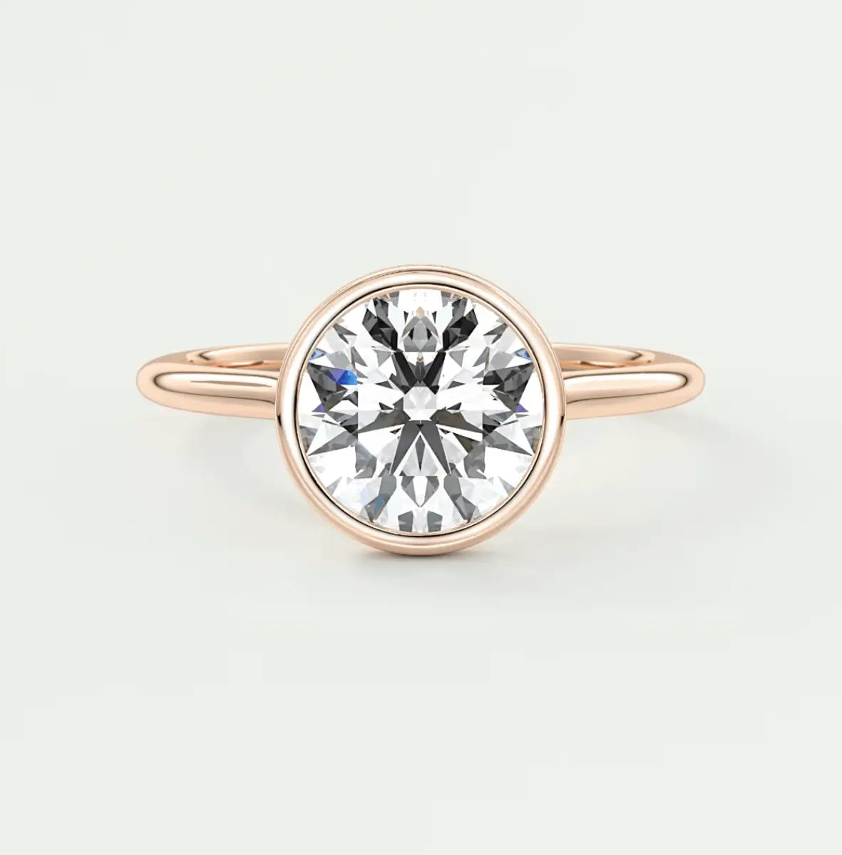 Rose gold diamond engagement ring with a bezel setting and elegant band design.