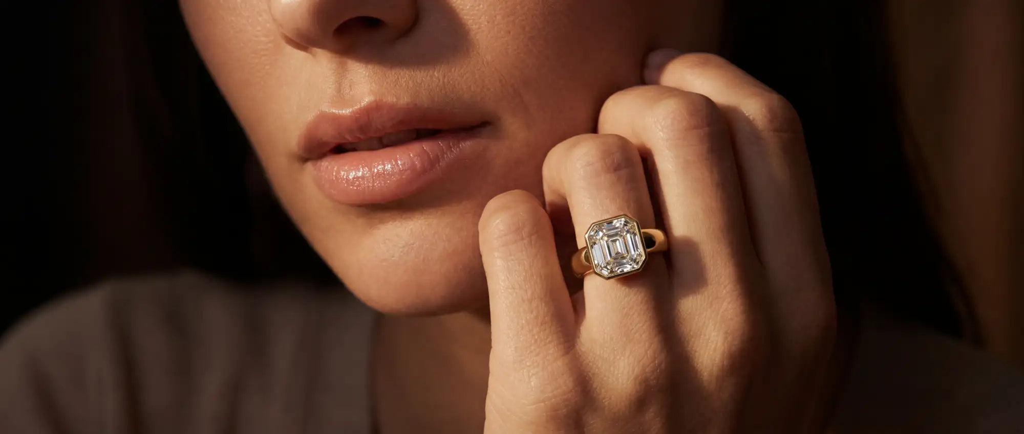 Close-up of a woman's hand wearing a diamond ring with a dark background