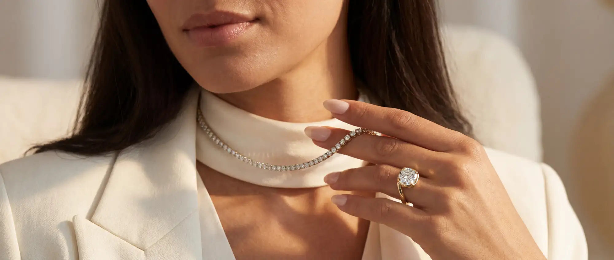 Close-up of a woman wearing a pearl necklace and ring, with a blurred background.