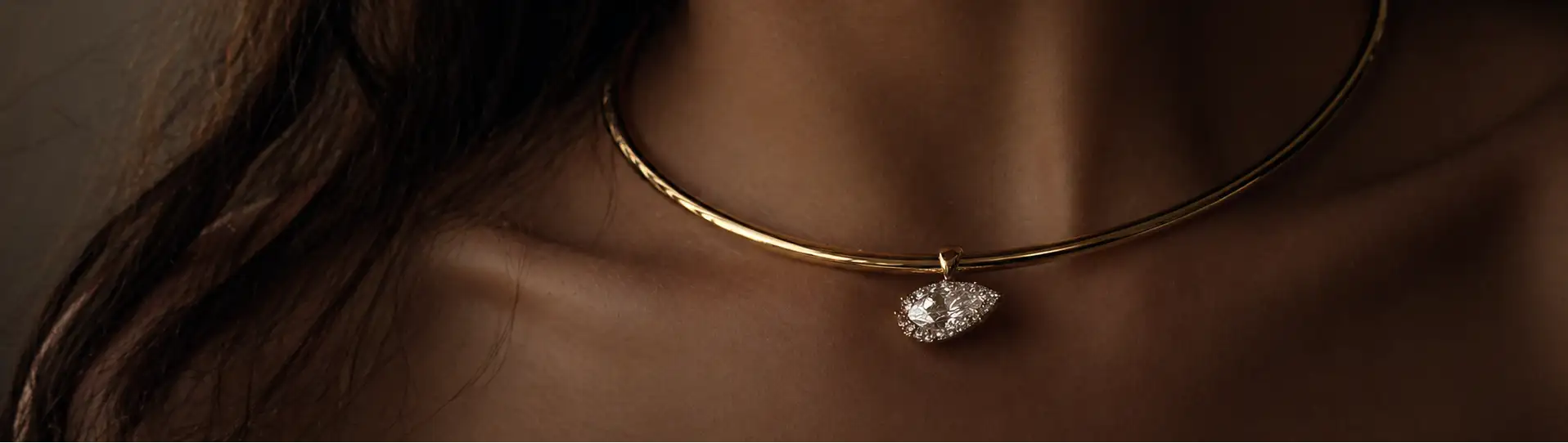 Close-up of a gold necklace with a heart-shaped pendant on a blurred background