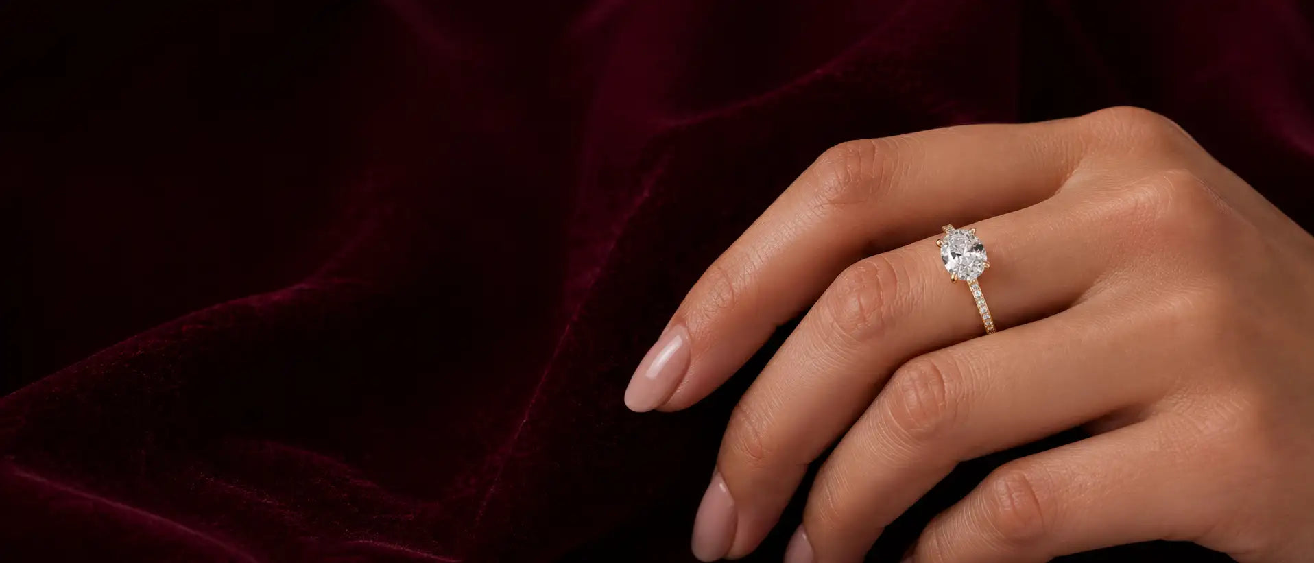 Hand wearing a diamond ring on a dark background