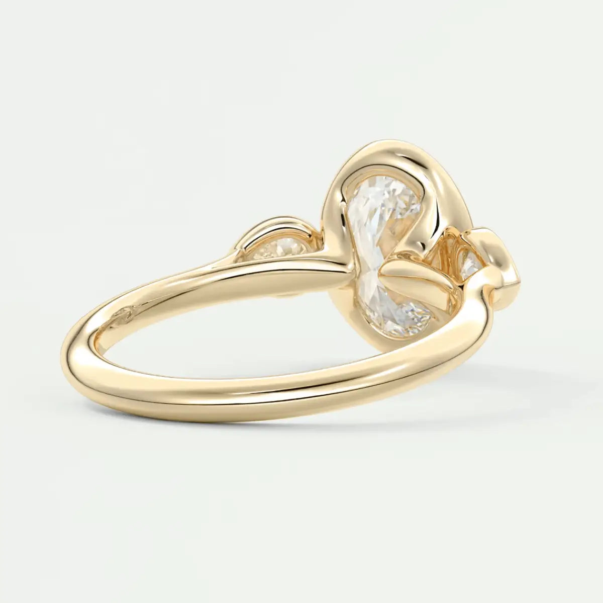 Gold heart-shaped diamond engagement ring with a pear-cut center stone and small round diamonds on the sides.