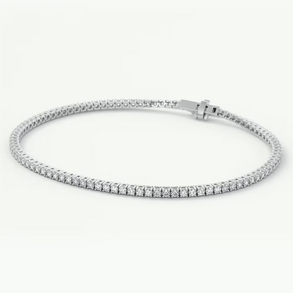 A silver tennis bracelet with a row of small clear gemstones and a sliding clasp, photographed on a clean white background.