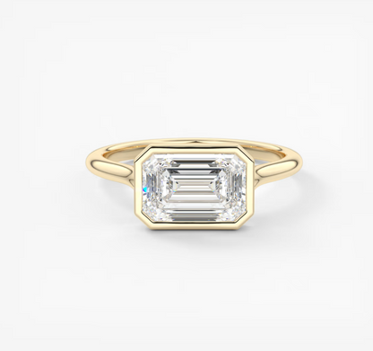 Gold ring with a emerald-cut diamond on a white background