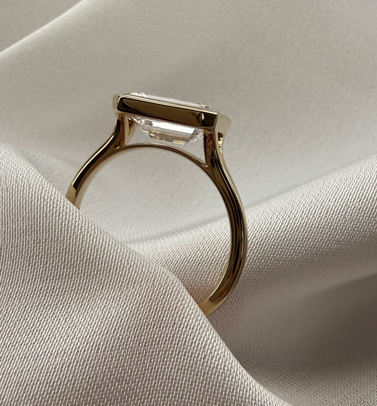Gold ring with a clear gemstone on a light fabric background