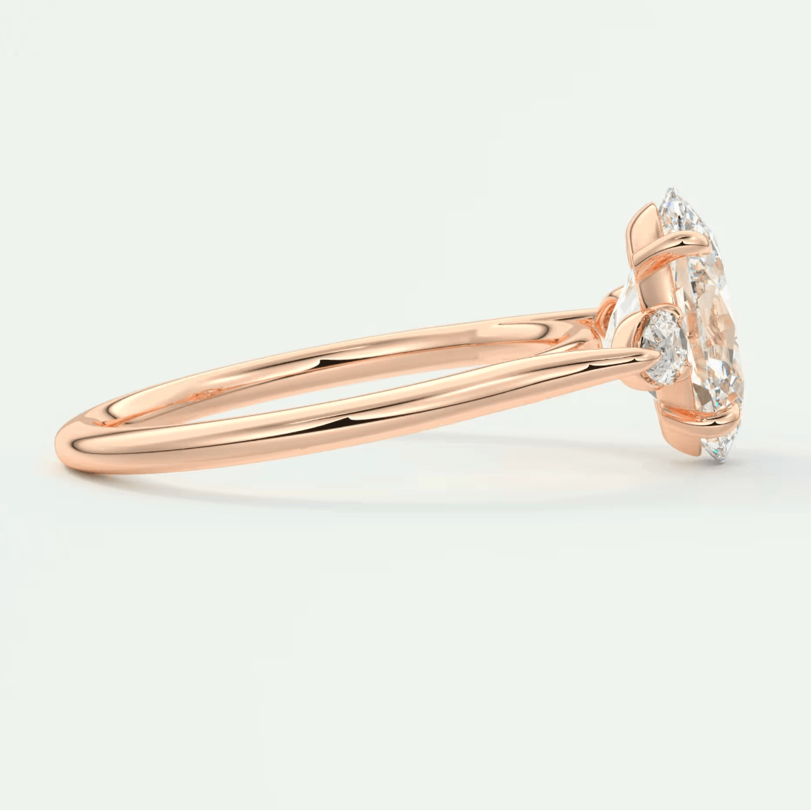 18-karat rose gold engagement ring with a marquise-cut diamond and two smaller diamonds on the band.
