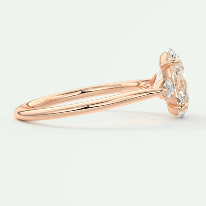 18-karat rose gold engagement ring with a marquise-cut diamond and two smaller diamonds on the band.