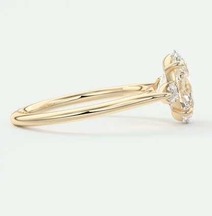 18k yellow gold engagement ring with a marquise-cut diamond and two smaller diamonds on either side.