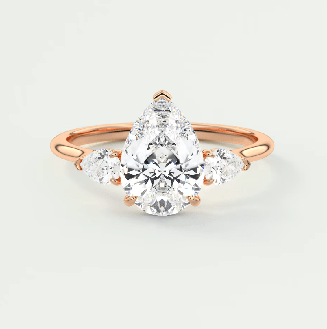18k rose gold engagement ring with a pear-shaped diamond and smaller diamonds on the band.
