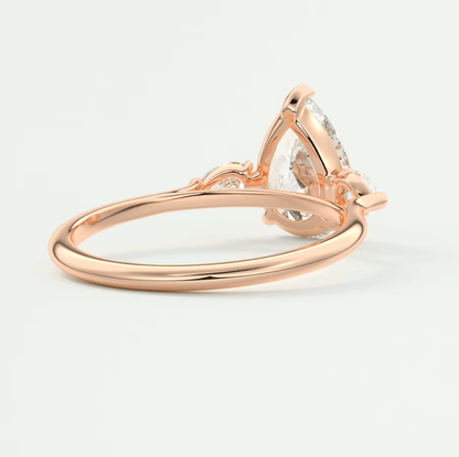Rose gold diamond engagement ring with a pear-shaped stone and delicate floral accents.