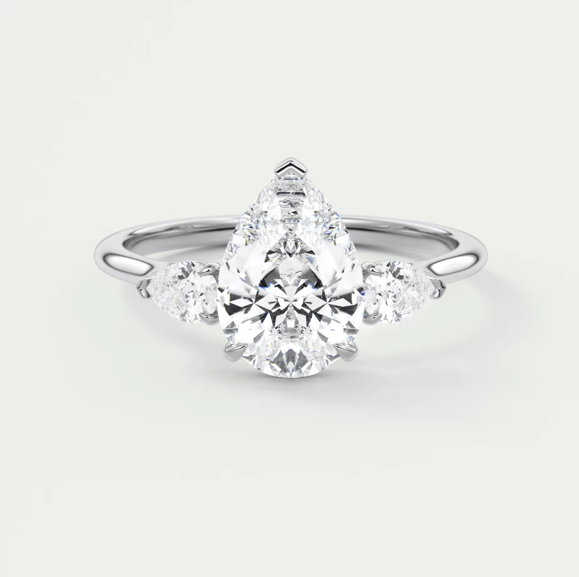 18-karat white gold engagement ring with a pear-shaped diamond and two smaller round diamonds on each side.