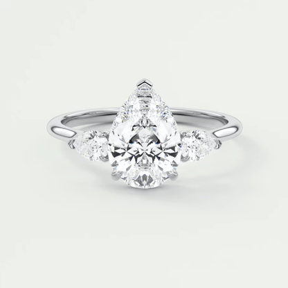 18-karat white gold engagement ring with a pear-shaped diamond and two smaller round diamonds on each side.