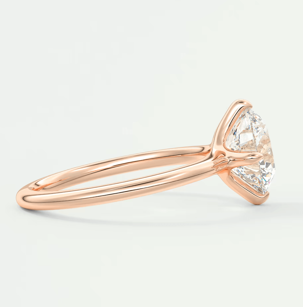 18-karat rose gold engagement ring with a round diamond center stone and small side diamonds.