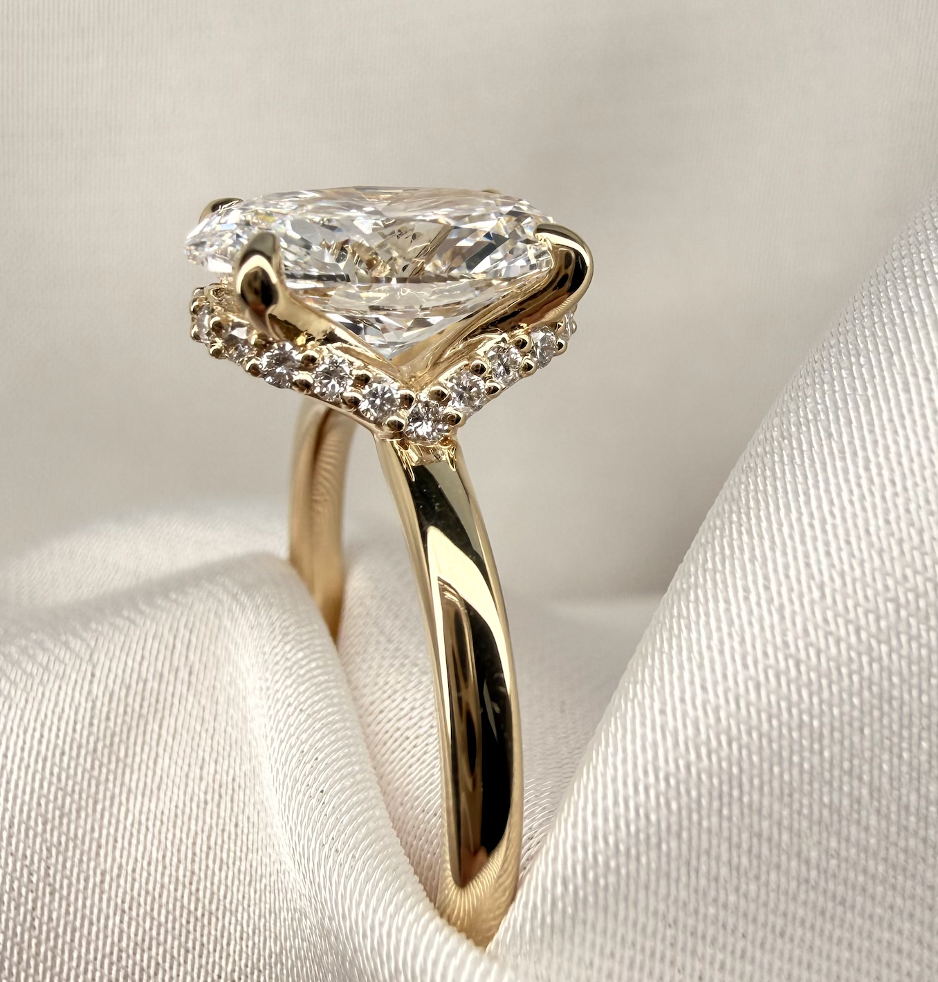 Gold ring with a large diamond on a white fabric background