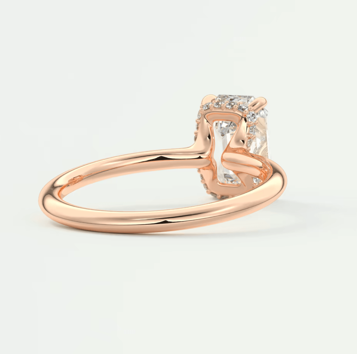 Rose gold engagement ring with a cushion-cut diamond and small diamonds on the band, featuring a halo design.