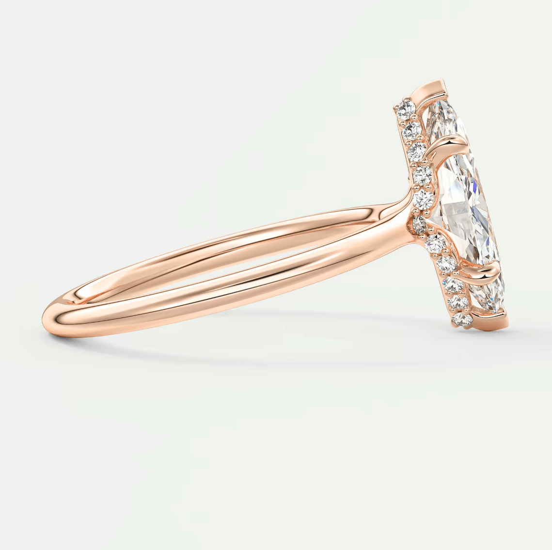 Rose gold engagement ring with marquise-cut diamond and small round diamonds set in a delicate band.