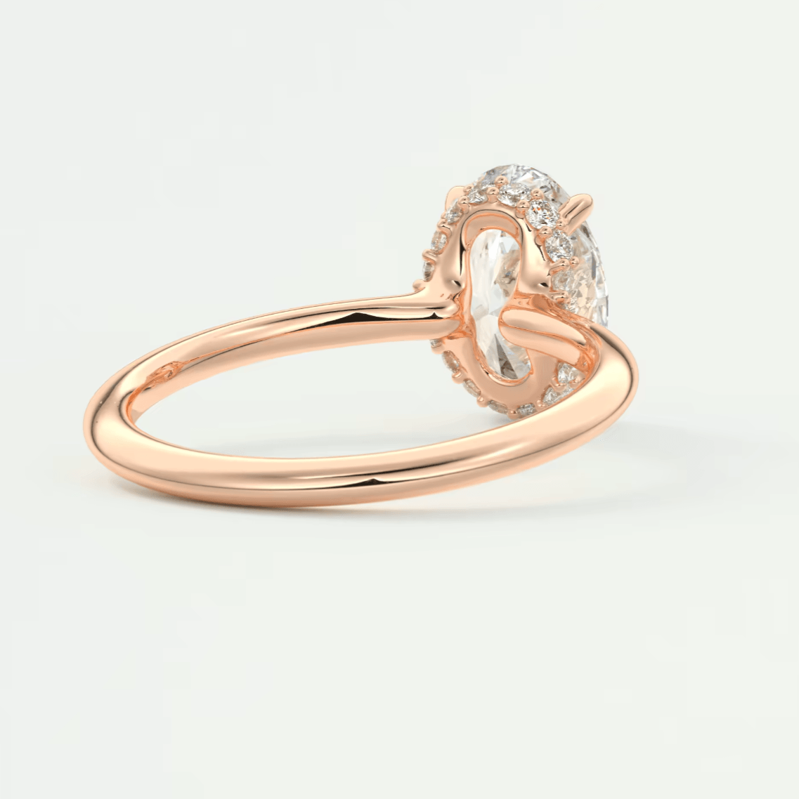 Rose gold diamond engagement ring with an oval-cut center stone and a halo of smaller diamonds.