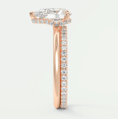 18k rose gold engagement ring with a pear-shaped diamond and halo of smaller diamonds.