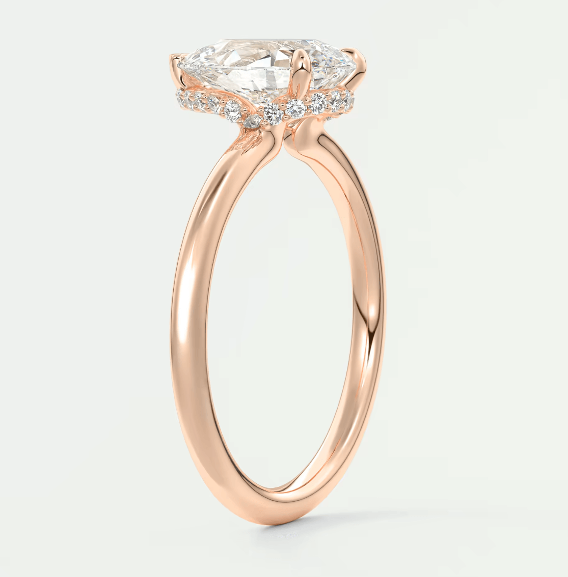 Rose gold engagement ring with a cushion-cut diamond and smaller diamonds set in the band, featuring an elegant halo design.