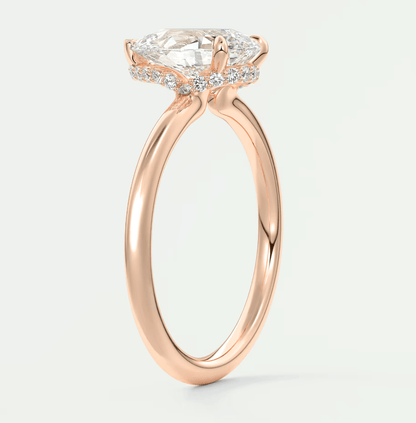 Rose gold engagement ring with a cushion-cut diamond and smaller diamonds set in the band, featuring an elegant halo design.