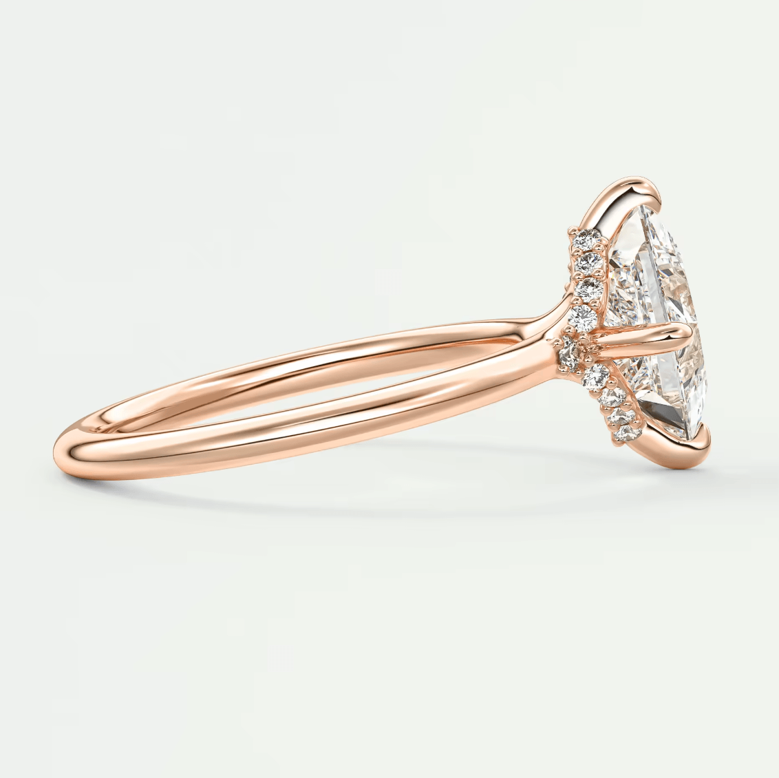 18-karat rose gold engagement ring with a marquise-cut diamond and small round diamonds set in the band.