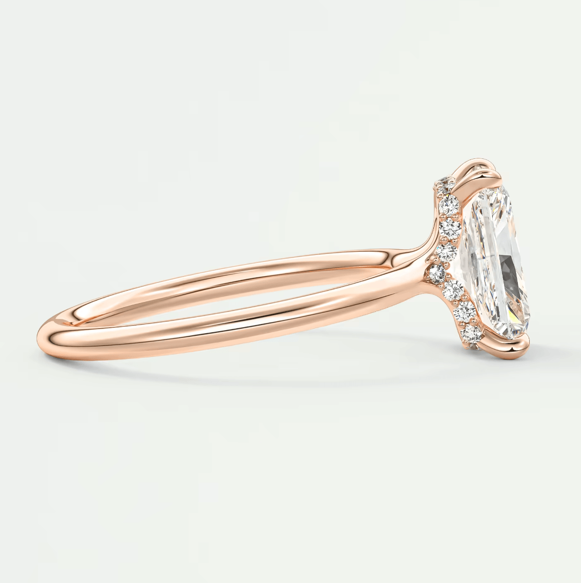 Rose gold diamond engagement ring with an emerald cut center stone and small diamonds on the band.