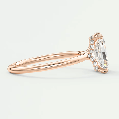 Rose gold diamond engagement ring with an emerald cut center stone and small diamonds on the band.