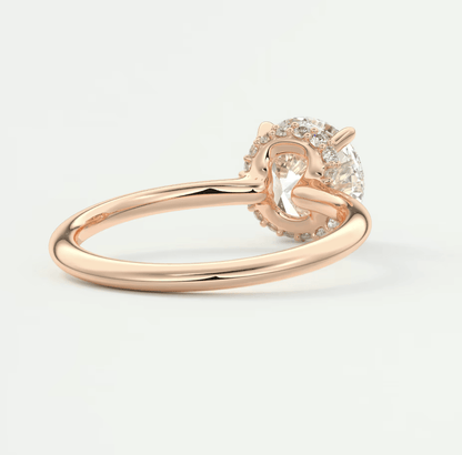 Rose gold diamond engagement ring with a round center stone and small side diamonds set in a halo design.